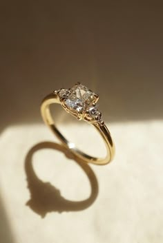 a yellow gold ring with two diamonds on it's sides, sitting on a white surface