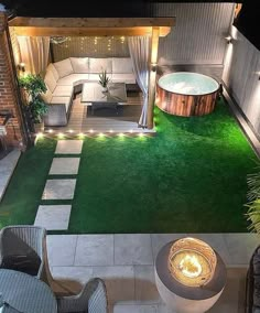 an outdoor living area is lit up at night with lights on the grass and a hot tub in the middle