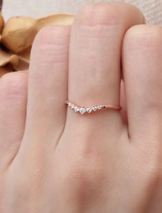 a woman's hand with a diamond ring on top of her finger, next to a flower