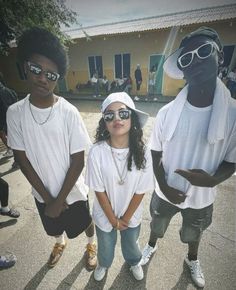 three young people standing next to each other in front of a building with sunglasses on