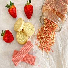 some cookies and strawberries are next to a jar of candy canes on the table