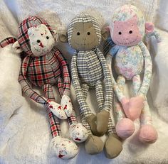 three stuffed animals sitting on top of a white blanket