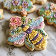 decorated cookies are arranged on a marble countertop with flowers and a bee in the center