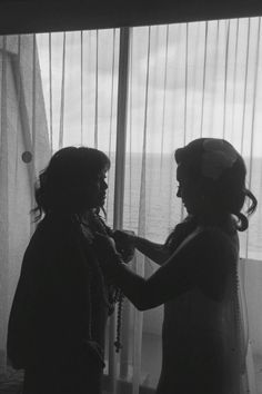 two women standing next to each other in front of a window looking out at the ocean