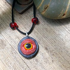 a necklace with an eye on it sitting on a wooden table next to a potted plant