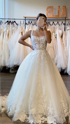 a woman taking a selfie while wearing a wedding dress in a bridal shop