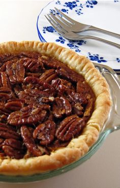 a pecan pie sitting on top of a table next to a fork and knife