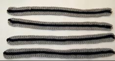 three crocheted black and grey ties on a white surface