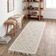 a white rug with tassels on top of it in a living room next to a book shelf