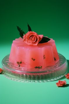 a pink cake sitting on top of a glass plate covered in icing and flowers