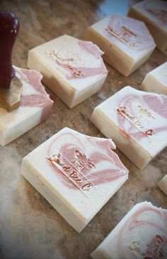 some soaps are sitting on a counter with a stamper in front of them