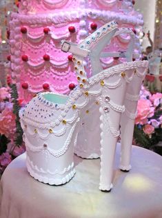 a white high heeled shoe is on display in front of pink and red flowers