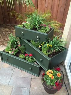 three green planters are stacked on top of each other with plants growing out of them