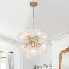 a chandelier hanging from the ceiling in a living room with white walls and furniture