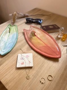 three different colored plates sitting on top of a wooden table next to jewelry and other items