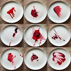 six plates with red paint on them sitting on top of a wooden table next to each other