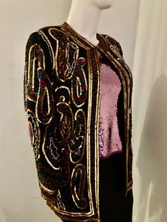 "sz 2x-bust 52\" waist 52\" hips 54\"  jacket length 34\"-sleeve length 26\" vintage 80s  below hip length silk  sequin beaded jacket good for a casual and special occasion look the fabric is exquisite  silk with beads and sequin  black with purple, pink, green, red and blue sequins low round neckline 4 front eye and hook closures wide shoulder with removable pads long sleeves  straight silhouette good quality construction fuller lined good condition dry clean only made in INDIA sustainable fash Festive Fitted Beaded Outerwear, Vintage Sequined Outerwear For Festive Season, Vintage Sequined Outerwear For Festive Occasions, Vintage Festive Sequin Outerwear, Fitted Multicolor Sequined Outerwear, Silk Sequined Long Sleeve Outerwear, Festive Beaded Fall Outerwear, Beaded Fall Festive Outerwear, Fitted Multicolor Evening Outerwear