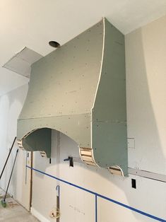 a large metal object hanging from the side of a wall in a room under construction