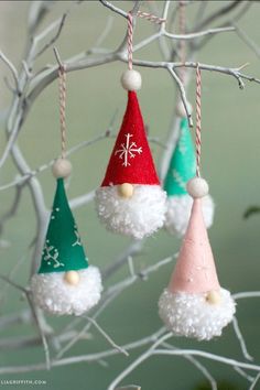 three christmas ornaments hanging from a tree with white and red hats on them, all decorated in pom - poms