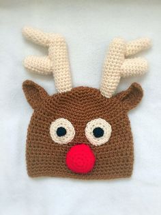 a crocheted reindeer hat with red nose and antlers on it's head