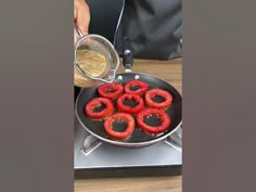 a person cooking hot dogs in a frying pan