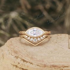 a close up of a gold ring with a white diamond in the center on top of a rock