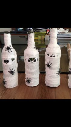 three wine bottles made out of toilet paper with spider webs and eyes on them