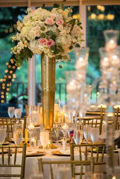 a tall vase filled with white and pink flowers on top of a dining room table