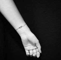 a person's hand with a small tattoo on the wrist and an arrow in the middle