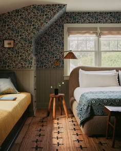 a bed sitting in a bedroom next to a window with blue and white wallpaper