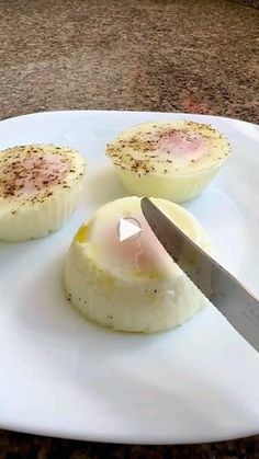 an egg being cut into small pieces on a white plate with a knife in it