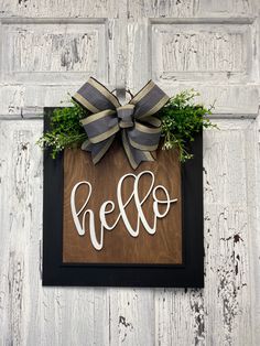 a wooden sign with the word hello on it and a bow hanging from it's side