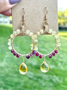 These earrings feature sparkly microfaceted gemstone beads and a citrine briolette wire wrapped in 14k gold filled wire. The gemstones in these earrings include: - citrine - tsavorite garnet - plum tourmaline The beads and briolette are wrapped in 14k gold filled wire in a hoop-like design with the citrine dangling below the hoop. All components of these earrings are handmade, and all of the gemstones are genuine, earth-mined gems. These earrings: - are hypoallergenic; suitable for those with me Round Faceted Beads Earrings As Gift, Hoop Jewelry With Faceted Beads For Gifts, Faceted Beads Dangle Hoop Earrings For Gifts, Round Crystal Earrings With Faceted Beads, Yellow Wire Wrapped Dangle Jewelry, Gold Wire Wrapped Briolette Teardrop Earrings, Citrine Briolette Earrings As Gift, Citrine Dangle Earrings With Ear Wire, Wire Wrapped Citrine Dangle Jewelry