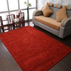 a living room area with a couch, chair and red rug on the hardwood floor