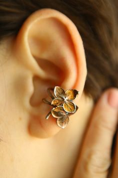 This gentle ear cuff is made of two hydrangea flowers. We have placed them on a convenient basis. These flowers grew in the botanical garden and after flowering we saved them and turned them into jewelry. Our magical technology has made it possible to give the flowers strength and preserve them in precious silver. So, if you or your friends love flowers, this cuff will be a wonderful purchase! Silver is covered with  yellow minerals. This is our development, which gives the metal a beautiful col Flower Ear Cuff, Adjustable Brown Jewelry For Spring, Nature-inspired Brown Flower-shaped Jewelry, Spring Brown Jewelry Gift, Brown Jewelry For Spring Gift, Spring Gift Brown Jewelry, Vintage Spring Wedding Jewelry, Unique Orange Flower Shaped Jewelry, Unique Orange Flower-shaped Jewelry