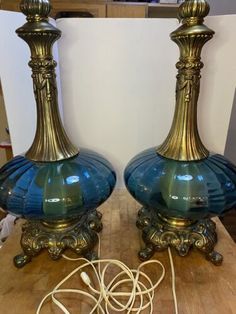 two blue glass lamps sitting on top of a wooden table next to an electrical cord