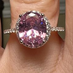 a close up of a person's hand with a pink ring on their finger