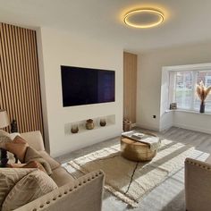 a living room filled with furniture and a flat screen tv mounted on the wall next to a window