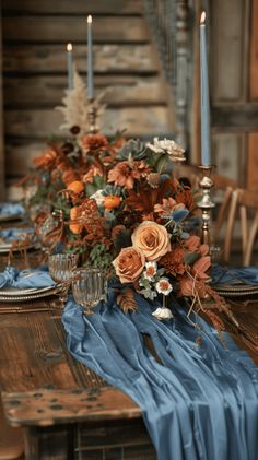 the table is set with blue cloths and flowers, candles, and napkins