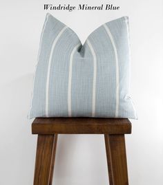 a blue and white striped pillow sitting on top of a wooden stool with the words windridge mineral blue