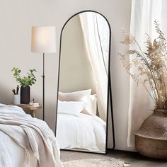 a bedroom with a large mirror on the wall next to a bed and plant in a vase