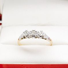 a three stone diamond ring in a red and white gift box with its lid open