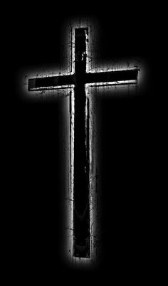 a black and white photo of a cross in the dark with light coming through it