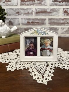 two photos are placed on a doily next to some books