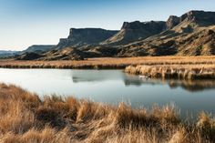 a lake surrounded by mountains and dry grass