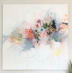 an abstract painting with many colors and shapes on the wall next to a potted plant