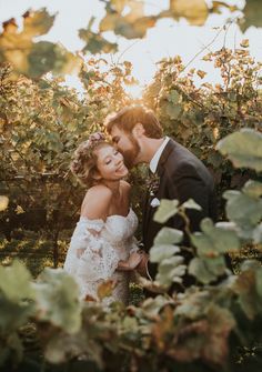 a bride and groom standing in the middle of a vineyard at sunset with sun shining through the vines