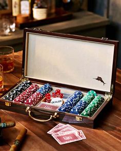 a wooden table topped with lots of poker chips and cards next to glasses filled with alcohol