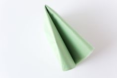 a green napkin folded on top of a white surface