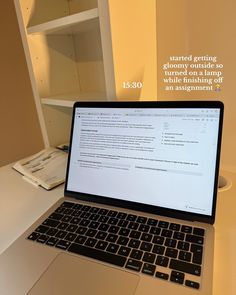 an open laptop computer sitting on top of a white desk next to a book shelf